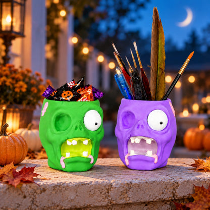 Zwei Zombie-Mehrzweckschalen für Halloween, eine grüne gefüllt mit Süßigkeiten und eine lila mit Pinseln und Stiften, auf einer mit Kürbissen dekorierten Terrasse