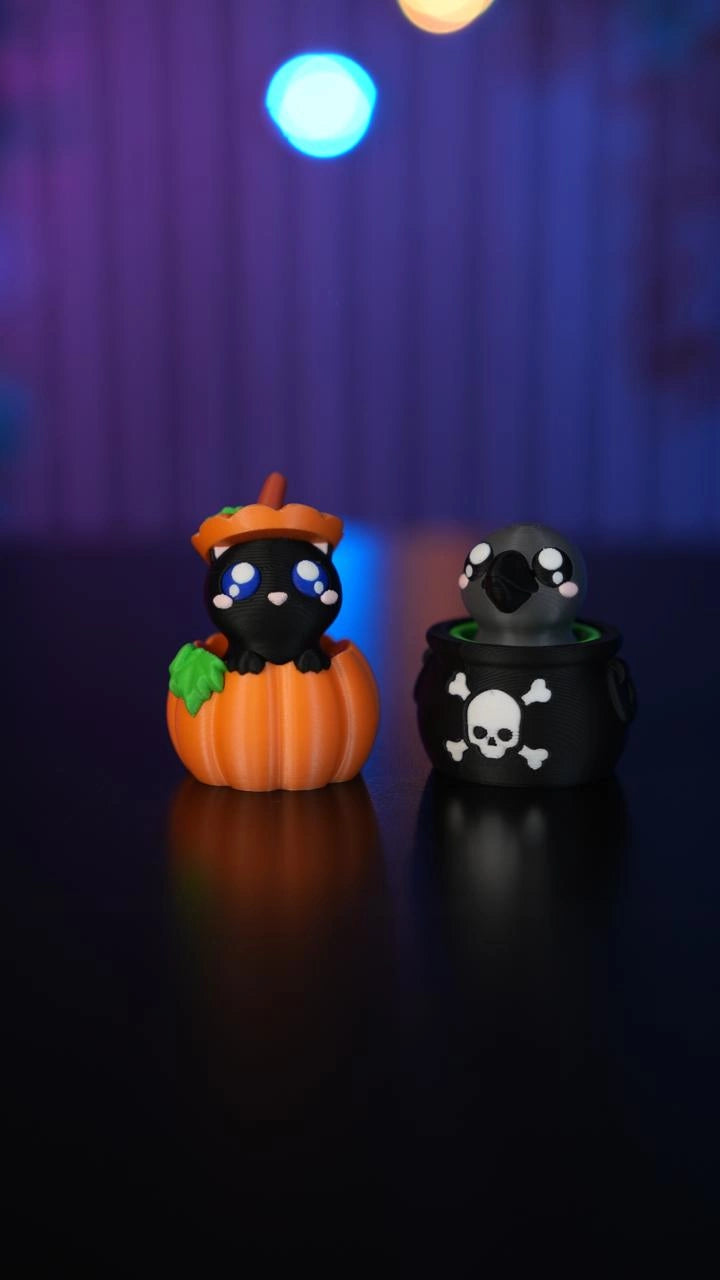 Halloween-Schlüsselanhänger-Clicker in Kürbisform neben dem schwarzen Kessel-Clicker mit Totenkopf und gekreuzten Knochen - Kokoroto