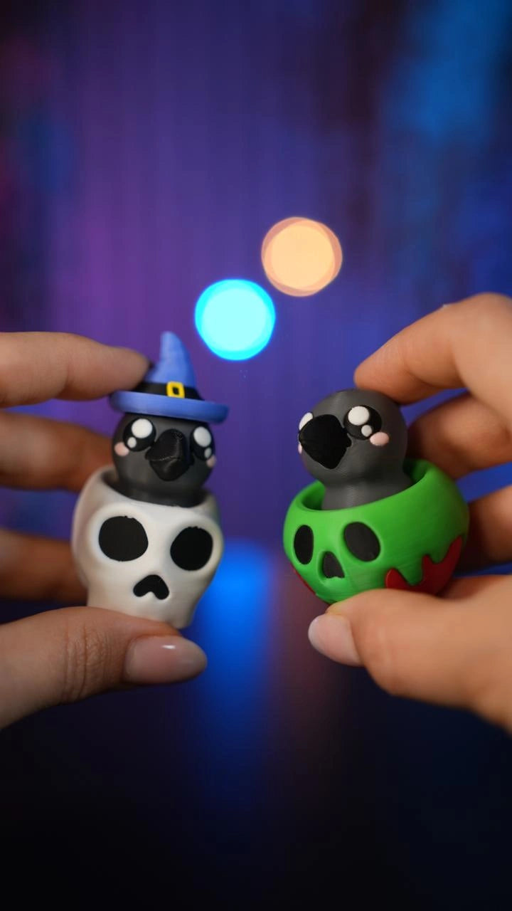 Hände halten zwei Halloween-Schlüsselanhänger-Clicker: einen in Form eines weißen Totenkopfs und einen als tropfenden grünen Kürbis - Kokoroto