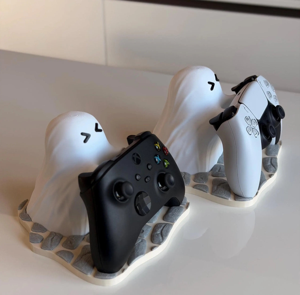 Soporte Ghost Buddy con los mandos de Xbox y PS5 colocados, vista trasera sobre bases de piedra - Kokoroto