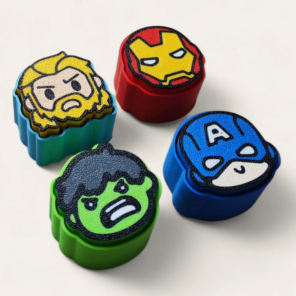 Superhero clicker keychains 3D printed, styled on a desk - Kokoroto