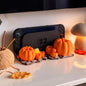 Halloween Dock mit Kürbissen für Nintendo Switch 2, mit eingesetzter Konsole, neben einem Wollknäuel und einer pilzförmigen Lampe - Kokoroto